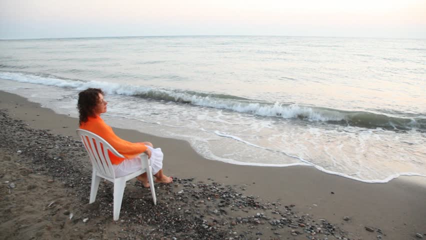 Young Curlyheaded Woman Sits On Plastic Chair Alone