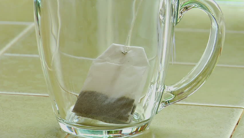 boiling-water-poured-over-a-tea-bag-in-a-clear-glass-coffee-cup-stock