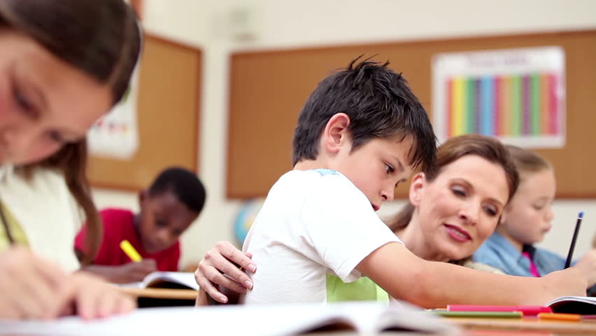 Teacher Explaining Something To A Pupil In The Classroom Stock Footage 