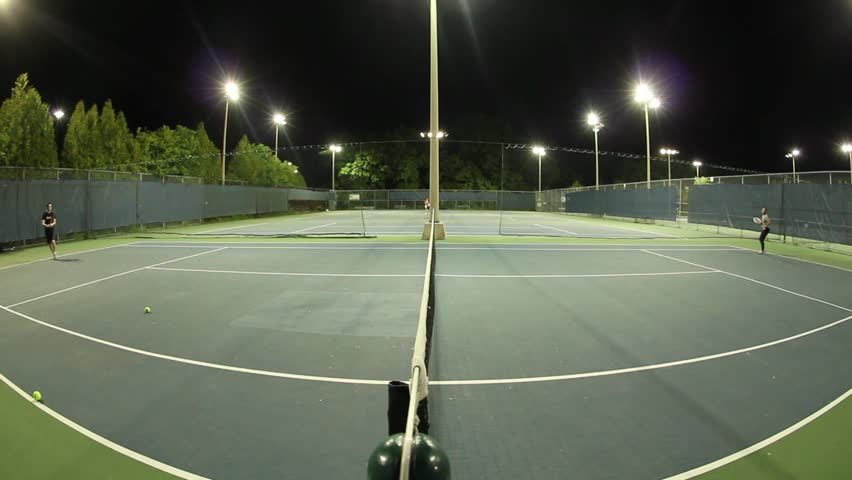 Playing Tennis On Some Beautiful Courts At Night Time Stock Footage
