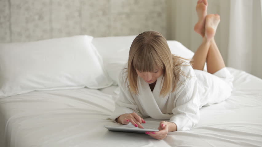 Cute Young Woman Lying On Bed Using Touchpad And Smiling Stock Footage