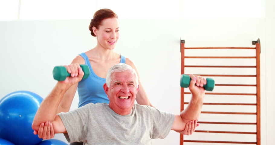 Exercise Class Sitting On Exercise Balls Lifting Hand Weights At The ...