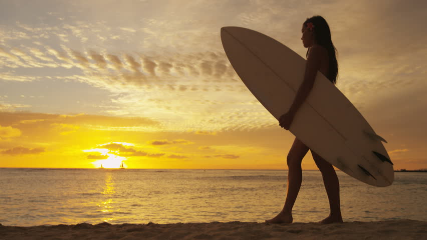 Surfer woman in silhouette walking with surfboard at sunset on tropical ...